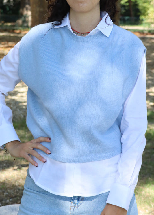 Poncho da donna in lana merino azzurra, senza maniche e con girocollo. La linea svasata con taglio asimmetrico — più corto sul davanti e più lungo sul retro — dona movimento e leggerezza. Realizzato artigianalmente dalla maglieria Strike Inside Abbigliamento, 100% italiana, è un capo di alta qualità che unisce la morbidezza e il calore della lana merino a uno stile raffinato e senza tempo.