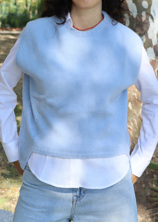 Poncho da donna in lana merino azzurra, senza maniche e con girocollo. La linea svasata con taglio asimmetrico — più corto sul davanti e più lungo sul retro — dona movimento e leggerezza. Realizzato artigianalmente dalla maglieria Strike Inside Abbigliamento, 100% italiana, è un capo di alta qualità che unisce la morbidezza e il calore della lana merino a uno stile raffinato e senza tempo.