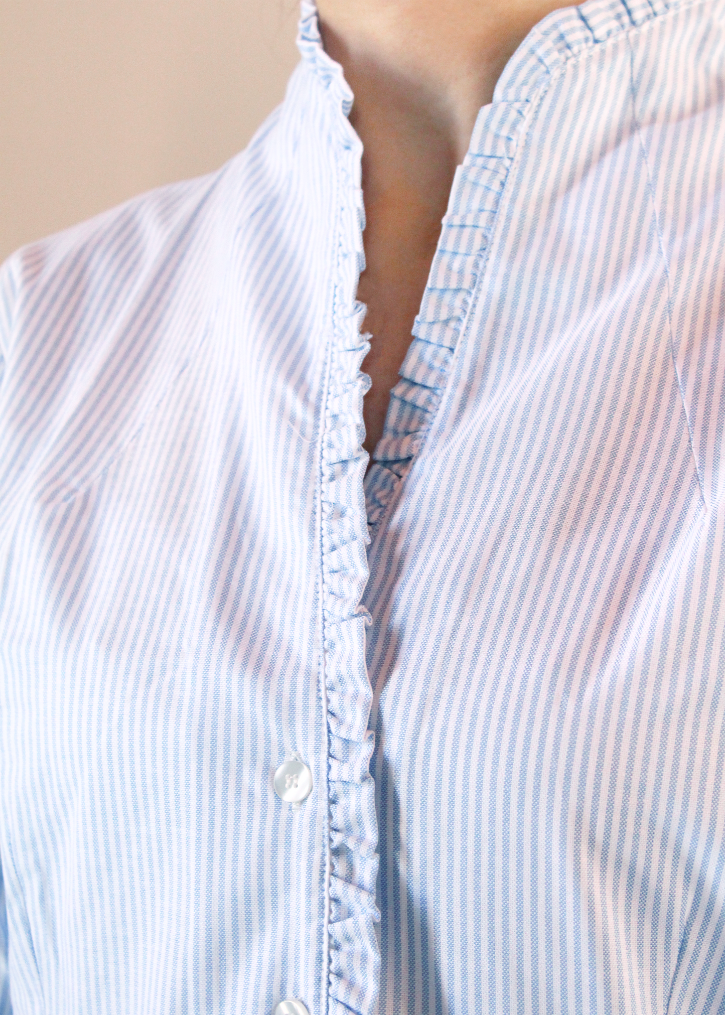 Camicia artigianale a righe fini azzurre e bianche in 100% cotone. Design elegante con scollo a V e rouches femminili. Realizzata dalla maglieria artigianale di Genova di Strike Inside. Made in Italy.