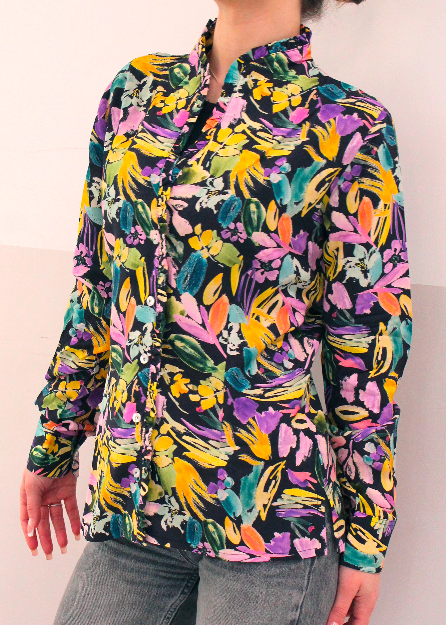 Camicia artigianale in 100% cotone con elegante fantasia floreale multicolor. Il design vivace e raffinato è arricchito da uno scollo a V con delicate rouches, per un tocco femminile e sofisticato. Realizzata con cura dalla maglieria artigianale di Genova di Strike Inside. Made in Italy.