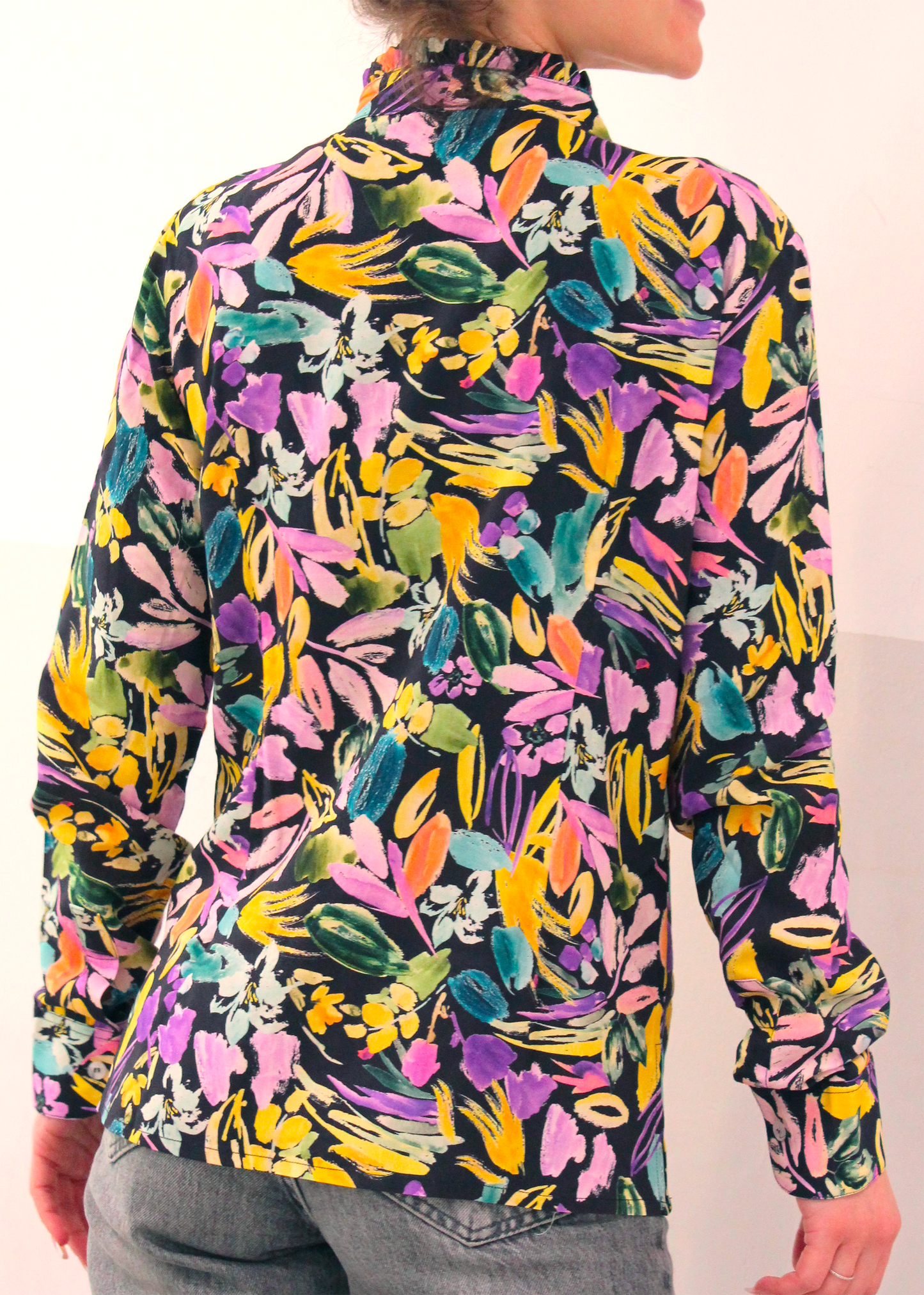Camicia artigianale in 100% cotone con elegante fantasia floreale multicolor. Il design vivace e raffinato è arricchito da uno scollo a V con delicate rouches, per un tocco femminile e sofisticato. Realizzata con cura dalla maglieria artigianale di Genova di Strike Inside. Made in Italy.