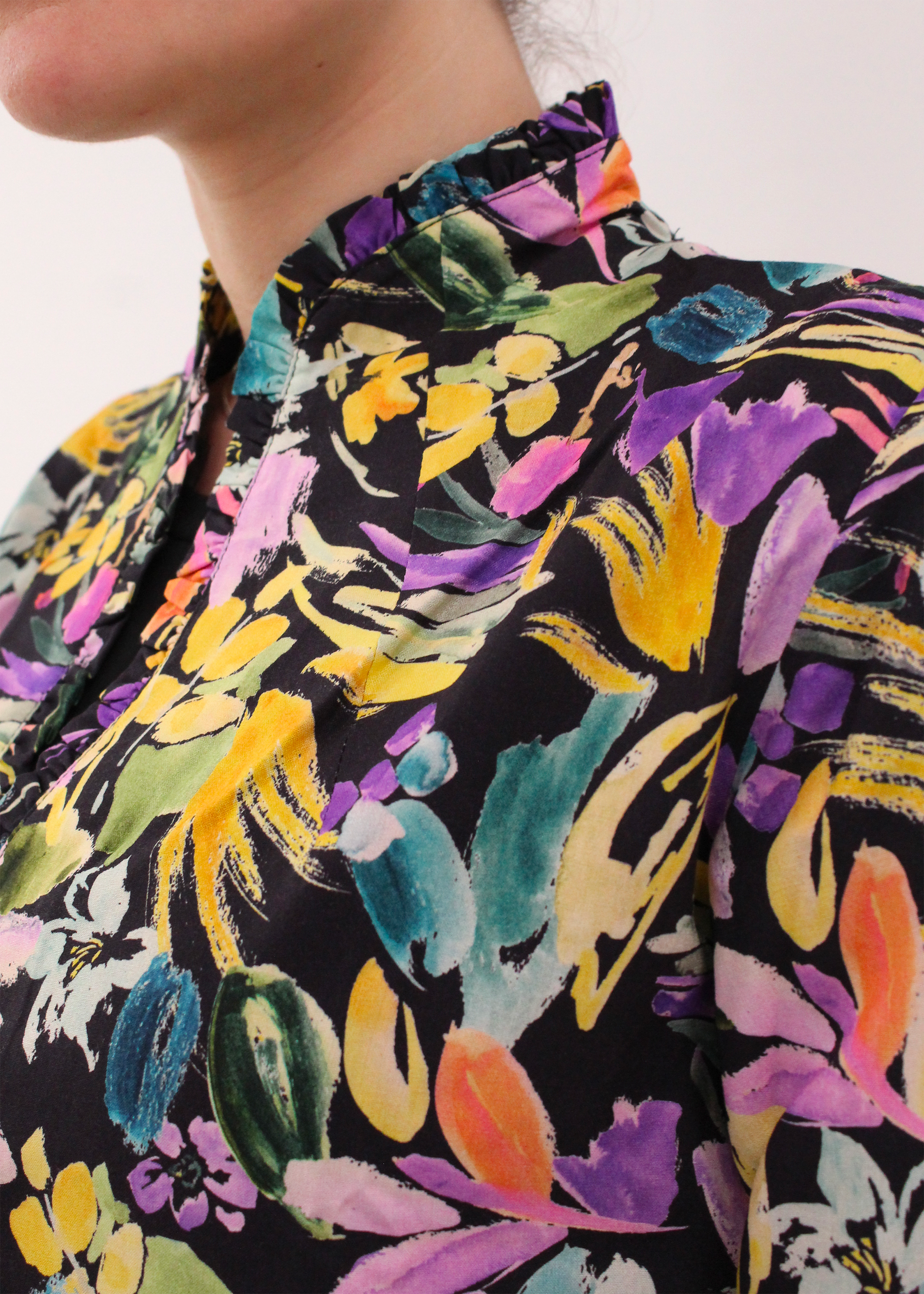 Camicia artigianale in 100% cotone con elegante fantasia floreale multicolor. Il design vivace e raffinato è arricchito da uno scollo a V con delicate rouches, per un tocco femminile e sofisticato. Realizzata con cura dalla maglieria artigianale di Genova di Strike Inside. Made in Italy.