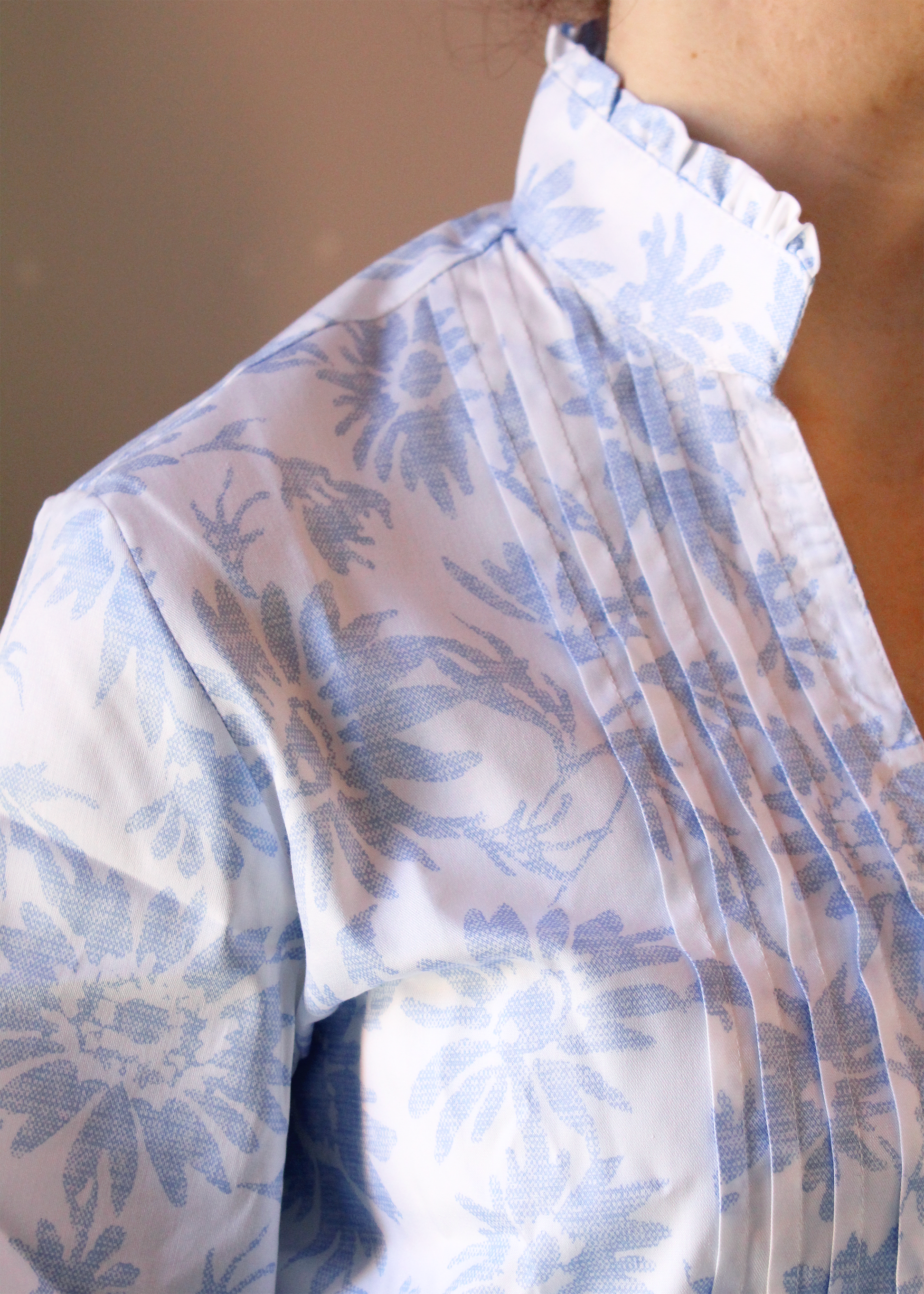 Camicia artigianale in 100% cotone, leggera e traspirante, con elegante fantasia floreale azzurra su base bianca. Design sofisticato con collo alla coreana e dettagli plissettati sul petto. Maniche a 3/4, ideale per le mezze stagioni. Realizzata con cura dalla maglieria artigianale di Genova di Strike Inside. Made in Italy.