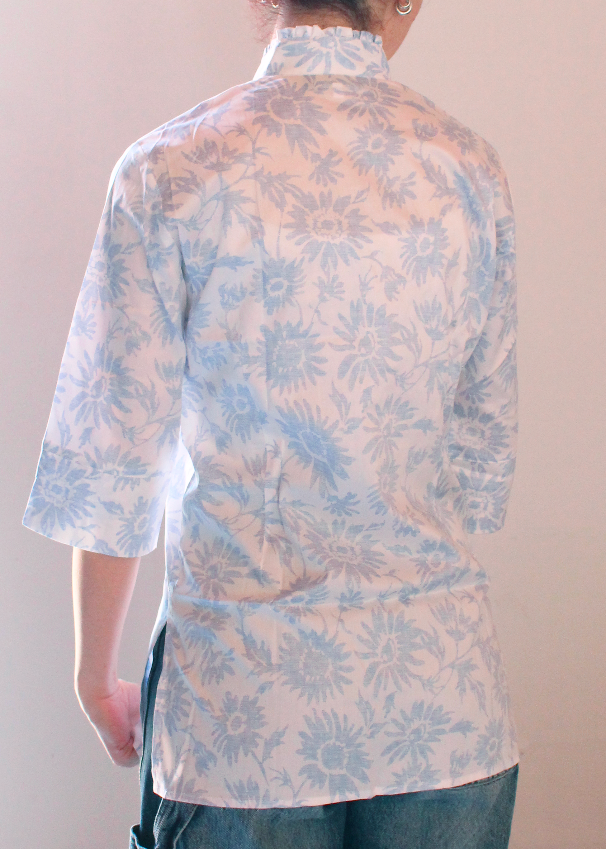 Camicia artigianale in 100% cotone, leggera e traspirante, con elegante fantasia floreale azzurra su base bianca. Design sofisticato con collo alla coreana e dettagli plissettati sul petto. Maniche a 3/4, ideale per le mezze stagioni. Realizzata con cura dalla maglieria artigianale di Genova di Strike Inside. Made in Italy.
