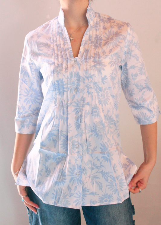 Camicia artigianale in 100% cotone, leggera e traspirante, con elegante fantasia floreale azzurra su base bianca. Design sofisticato con collo alla coreana e dettagli plissettati sul petto. Maniche a 3/4, ideale per le mezze stagioni. Realizzata con cura dalla maglieria artigianale di Genova di Strike Inside. Made in Italy.