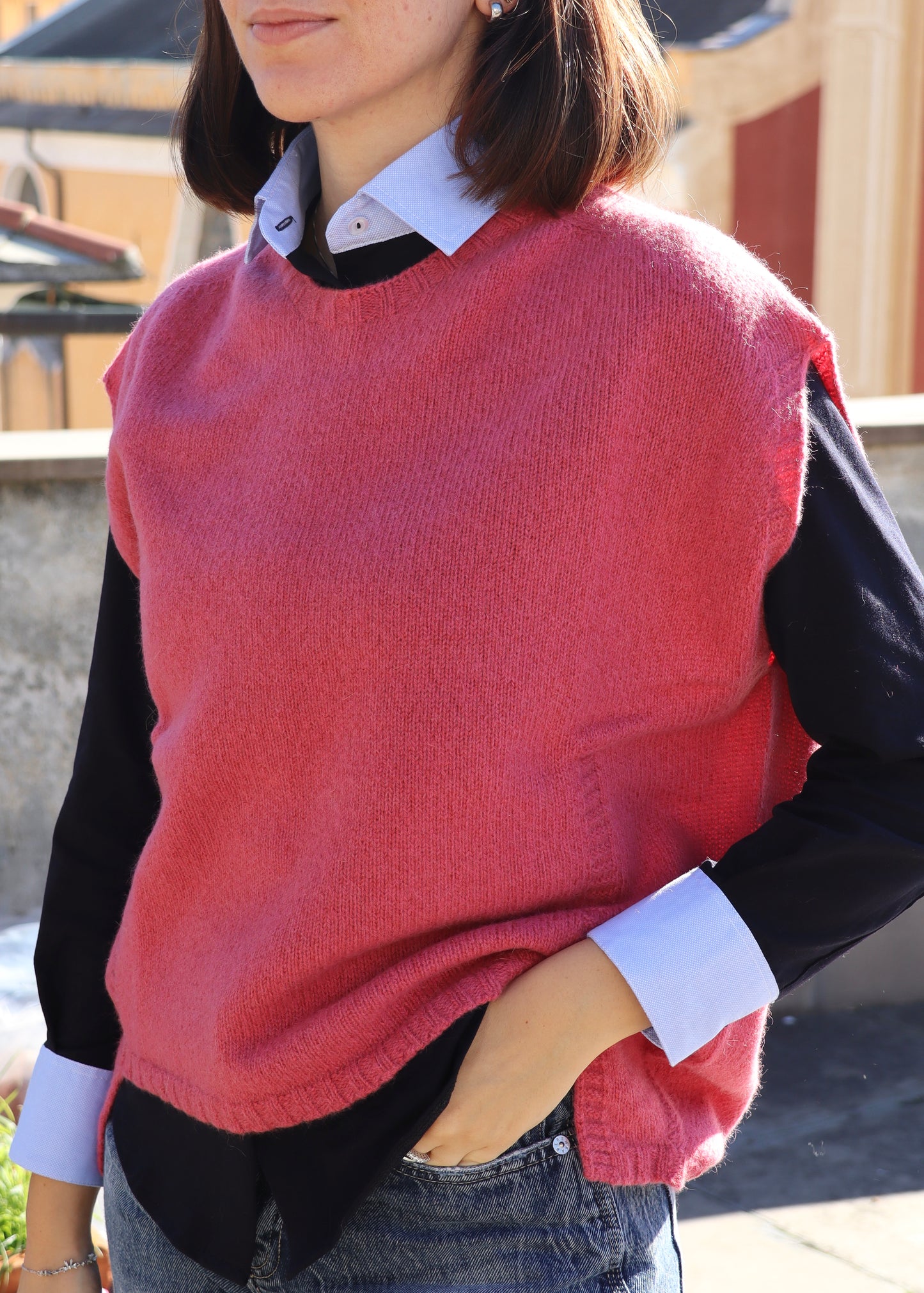 Camicia da donna in jersey di cotone elasticizzato (95% cotone, 5% elastan) di Strike Inside Abbigliamento, realizzata artigianalmente in Italia. Modello con colletto e polsini a contrasto in tessuto effetto camicia, dal taglio sfiancato e vestibilità morbida. Elegante e confortevole, segue la silhouette senza costringerla. Perfetta per un look curato e versatile, adatta a ogni occasione. Indossata con maglione senza maniche rosa.