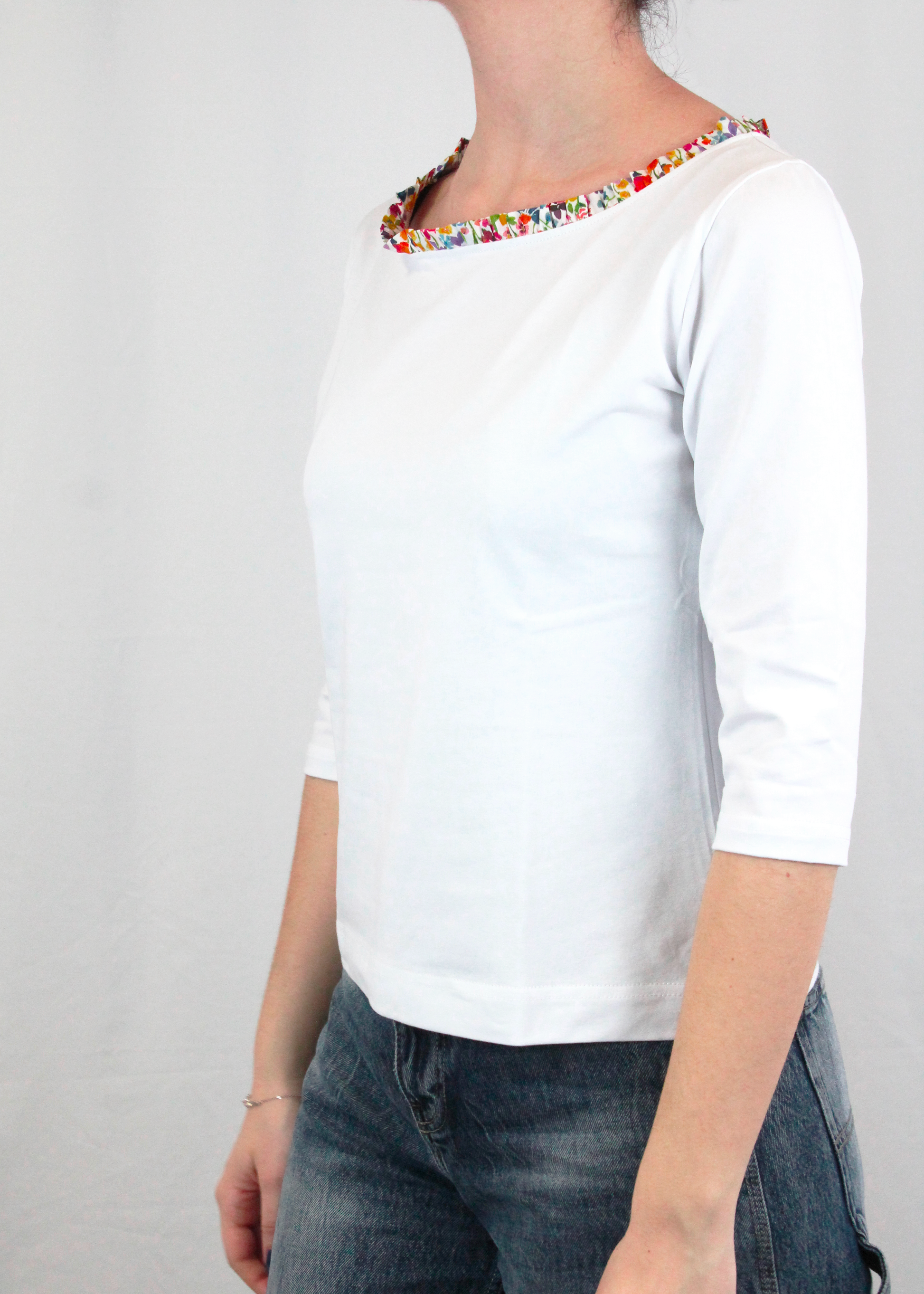 Maglietta artigianale in cotone elasticizzato con scollo a barchetta e delicate rouches. Morbida, confortevole e raffinata, con maniche a tre quarti per un look versatile e femminile. Disponibile in vari colori: naturale, bianco, blu, verde, rosso, rosa e altri. Realizzata con cura dalla maglieria artigianale di Genova di Strike Inside. Made in Italy.