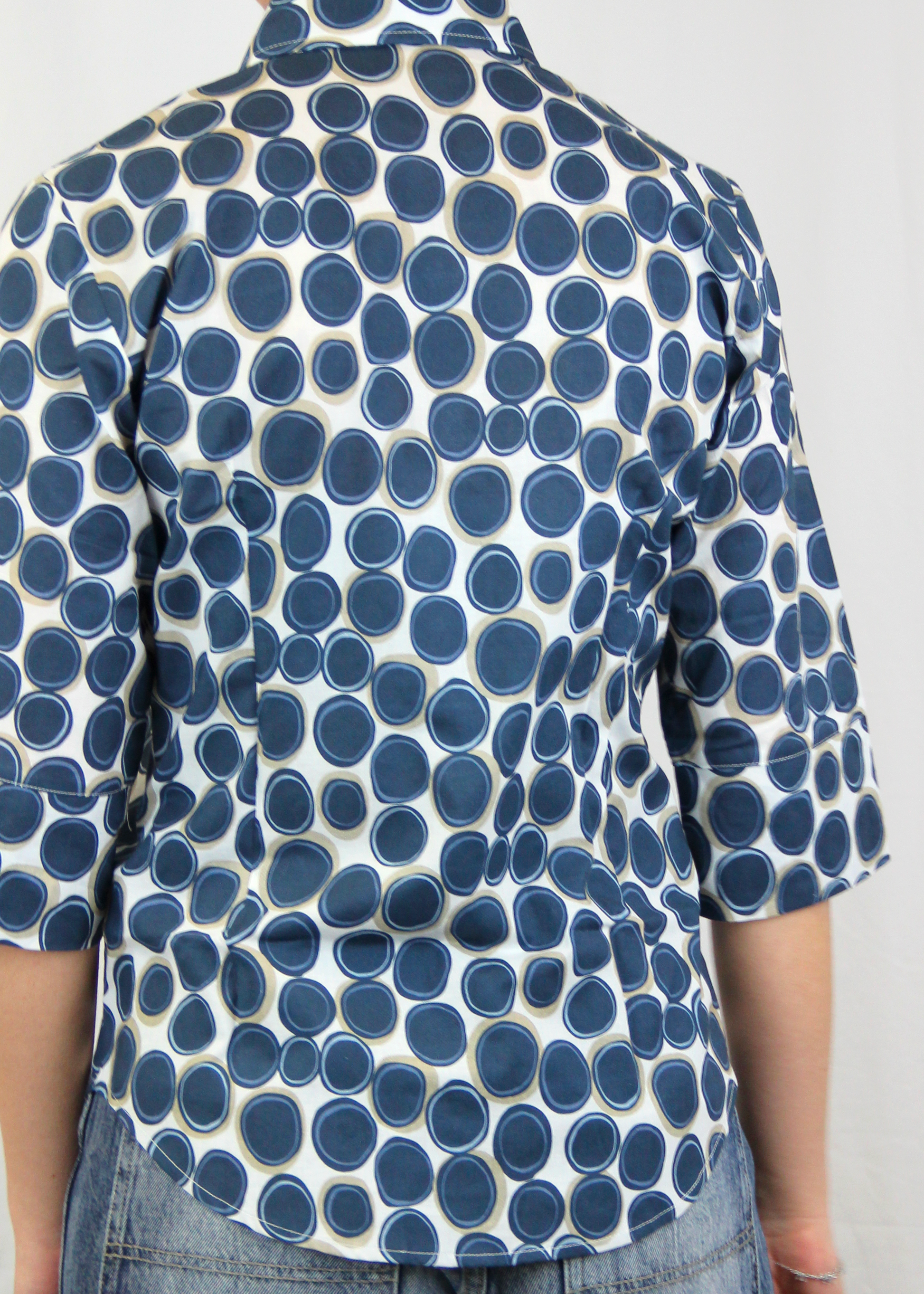 La camicia con manica a 3/4 è realizzata artigianalmente in 100% cotone leggero di alta qualità. Il taglio classico è arricchito dalla manica a 3/4, che conferisce un'eleganza informale, rendendo il capo perfetto per tutte le stagioni. La fantasia con cerchi, disponibile in verde e blu, aggiunge un tocco di originalità senza perdere la sobrietà. Un'ottima scelta per chi cerca uno stile curato e distintivo, ogni giorno. Made in Italy, per un look sofisticato e contemporaneo.
