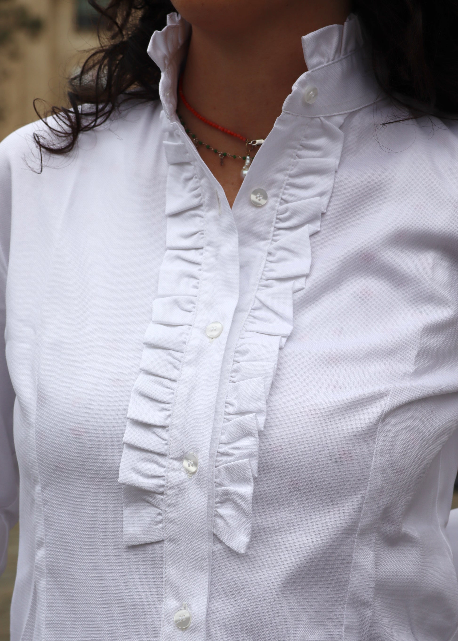 Camicia da donna in cotone con rouches decorative sul petto e sul colletto. Un modello femminile e raffinato, caratterizzato da dettagli romantici che donano volume e movimento. Ideale per un look elegante e distintivo, adatto sia a contesti casual chic che a occasioni formali.