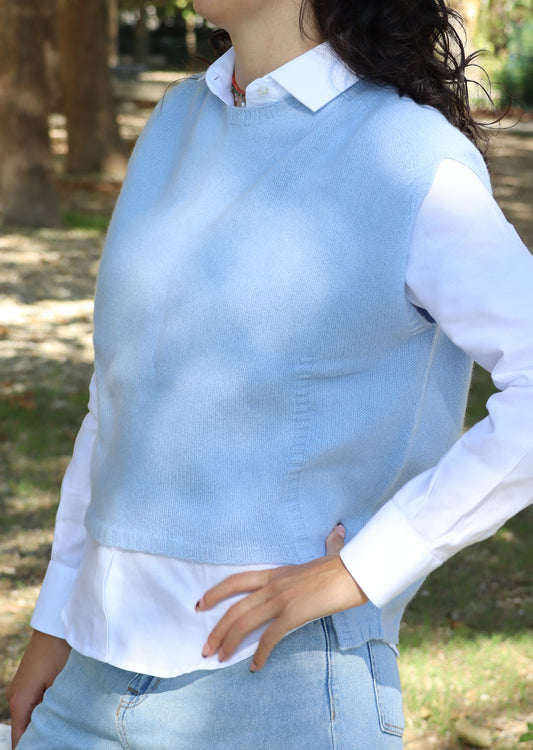 Poncho da donna in lana merino azzurra, senza maniche e con girocollo. La linea svasata con taglio asimmetrico — più corto sul davanti e più lungo sul retro — dona movimento e leggerezza. Realizzato artigianalmente dalla maglieria Strike Inside Abbigliamento, 100% italiana, è un capo di alta qualità che unisce la morbidezza e il calore della lana merino a uno stile raffinato e senza tempo.